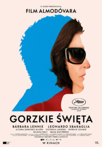 Na plakacie widoczny jest profil kobiety w dużych, ciemnych okularach przeciwsłonecznych. Jej sylwetka częściowo nakłada się na dużą, intensywnie niebieską abstrakcyjną formę. Tło jest jasnoróżowe. U góry znajduje się napis „Film Almodóvara”, a poniżej tytuł „Gorzkie święta”. Na plakacie wymieniono m.in. Barbarę Lennie i Leonardo Sbaraglię. Widoczne jest również oznaczenie konkursu głównego Festiwalu w Cannes 2026 oraz informacja „W kinach”.