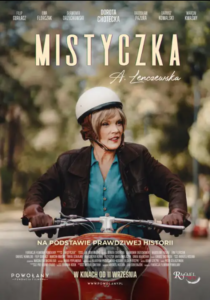Plakat przedstawia kobietę jadącą na skuterze. Kobieta ma na głowie biały kask, ubrana jest w ciemną kurtkę i niebieską koszulę. Znajduje się na tle rozmytej, zielonej scenerii z drzewami i ulicą. U góry plakatu widnieje duży tytuł „MISTYCZKA” oraz odręczny napis „A. Lenczewska”. Nad tytułem umieszczono nazwiska aktorów. W dolnej części znajduje się napis „NA PODSTAWIE PRAWDZIWEJ HISTORII”, informacje o filmie oraz data premiery „W KINACH OD 11 WRZEŚNIA”.